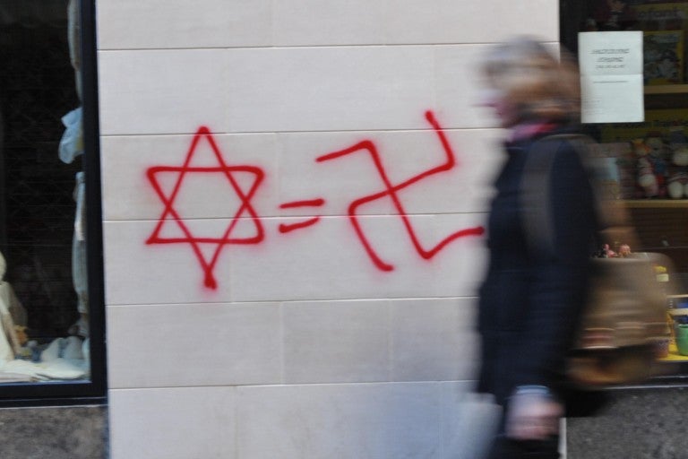 Photo of a Star of David, an equal sign, and a Swastika graffiti-ed on a wall