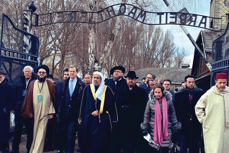 Photo of American Jewish Committee and Muslim World League Historic walking through the "Arbeit Macht Frei" gate at Auschwitz 