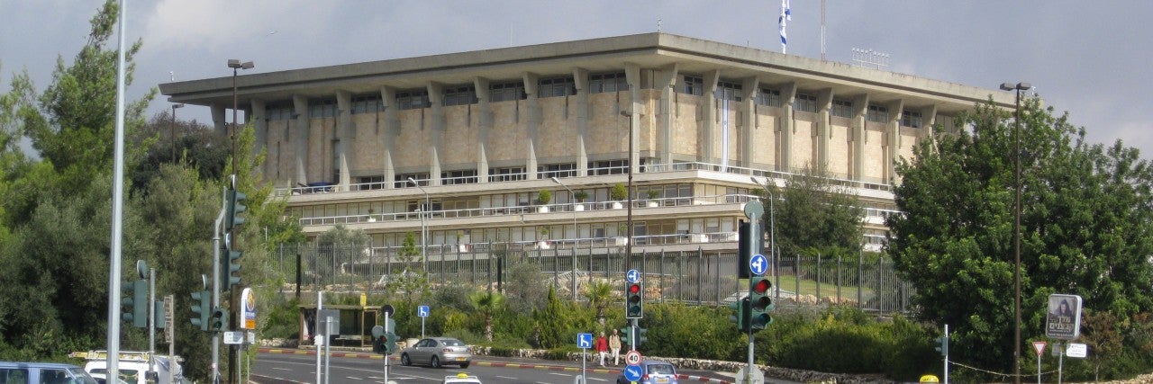Knessett building israeli parliment. large beige stone building in background, grey-blue sky
