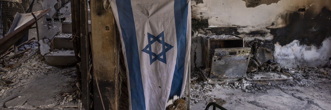 BE'ERI, ISRAEL - DECEMBER 20: Israeli flag hangs in destroyed house on December 20, 2023 in Be'eri, Israel. Families and supporters of hostages kidnapped by Hamas on Oct. 7 joined a tour of Kibbutz Be'eri held for journalists to mark 75 days since the attack. 