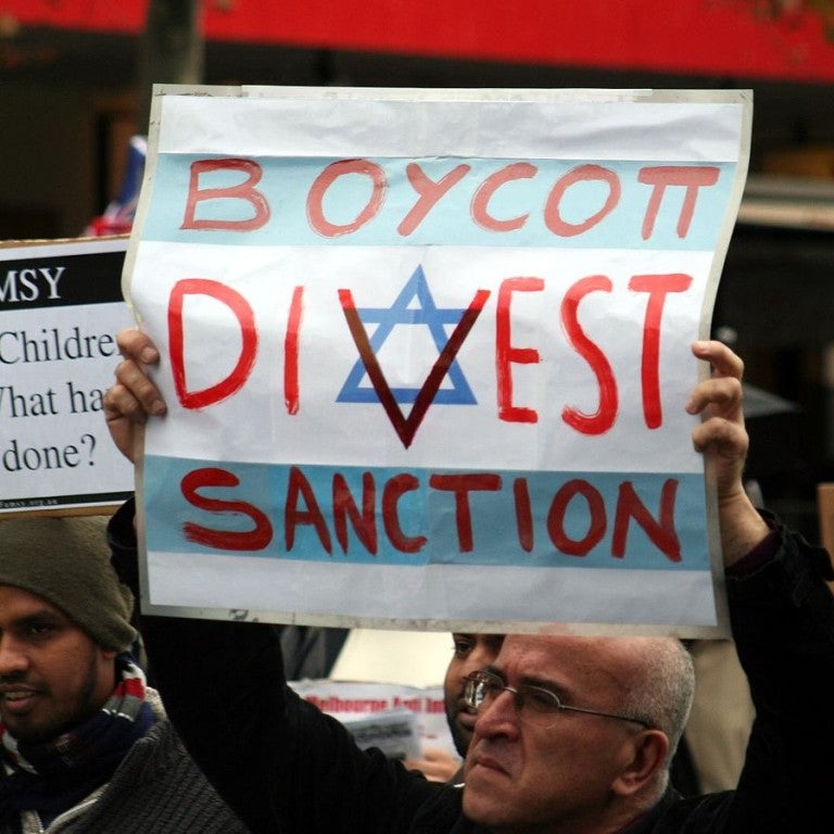 Protestor holding a boycott, divest, and sanction (BDS) sign